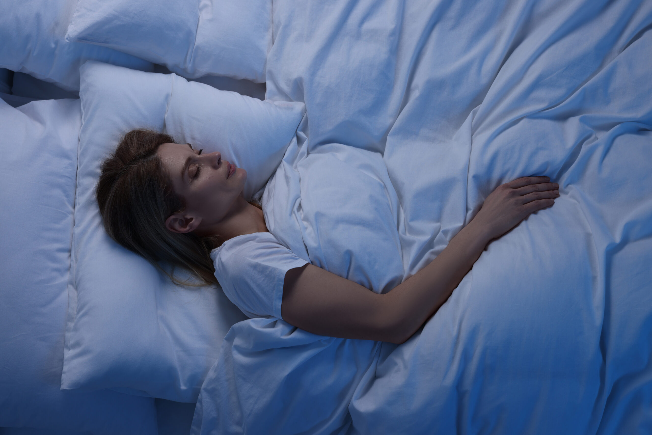 Woman sleeping in bed at night, above view
